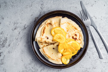 Plate of crepes with orange on gray background
