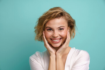 Beautiful woman smiling at camera while posing isolated over blue background