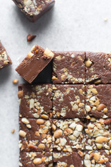 Top view of chocolate fudge with nuts on a marble board, chocolate fudge cut into pieces, fudge candy on a chopping board