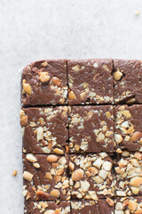 Top view of chocolate fudge with nuts on a marble board, chocolate fudge cut into pieces, fudge candy on a chopping board