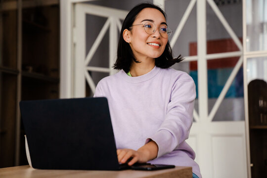 Smiling Asian Woman Working On Laptop While Sitting At Home