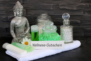 Schild mit Ölen, Buddha, Pflege Produkten und dem Wort Wellness- Gutschein.