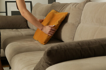 Woman arranging sofa cushion in living room	
