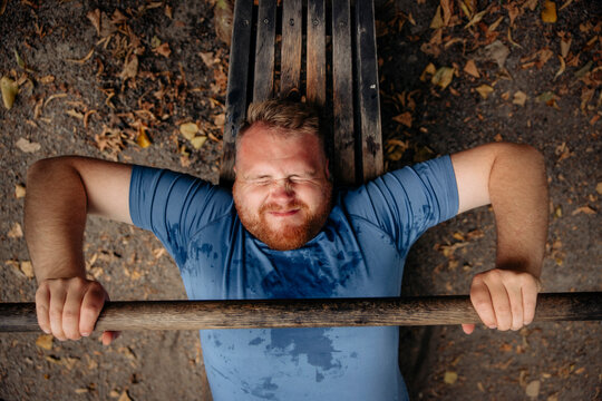 Directly above shot of determined obese man doing bench press at park