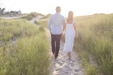 romantic couple from behind walking at beach hand in hand