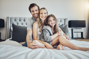 Love, relax and portrait of a family on a bed embracing, bonding and resting together at their home. Happiness, mother and father sitting and relaxing with their girl child in their bedroom in house.