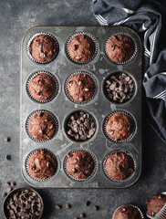 Overhead of tin of chocolate zucchini muffins on black background.