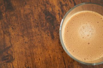 Cup of sparkling latte coffee on wooden table