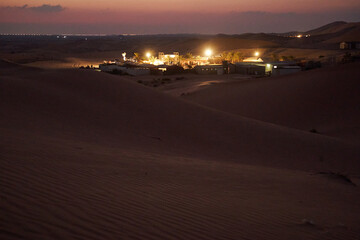 Night landscape with an oasis in the desert illuminated by lanterns.