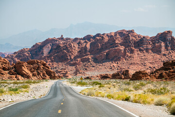 Winding road in the desert with reddish mountains in the bkgrnd