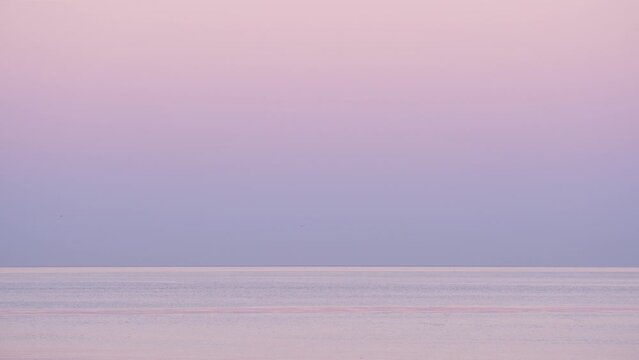 Calm sea and clear sky, gentle colors of nature before sunrise. Beautiful and peaceful view of Marmara Sea in the early morning hour. Sometimes sea gulls fly over the water