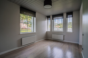 Classical empty room interior. The rooms have wooden floors and gray walls ,decorate with white moulding,there are white window looking out to the nature view.