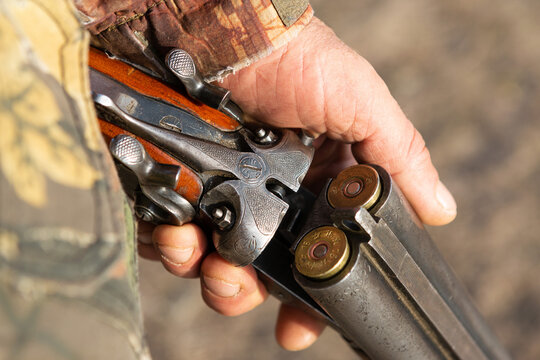 Midsection of man unloading shotgun while standing on field