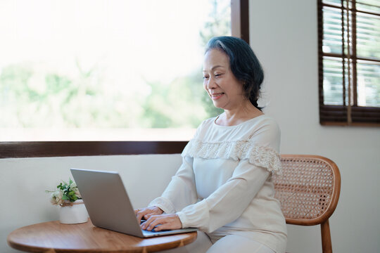 Portrait Of An Elderly Asian Woman In A Modern Pose Working On A Computer.