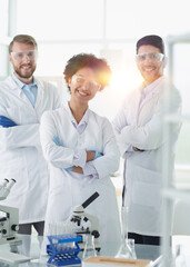 Smiling scientists looking at camera arms crossed in laboratory