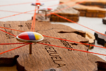 Venezuela flag on the pushpin and red threads on the wooden map. Travel or logistic routes....