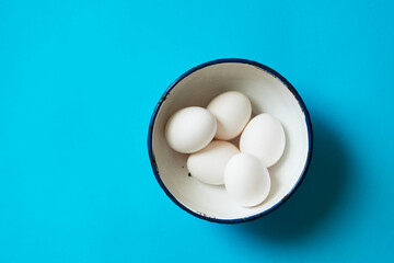 Eggs in a bowl on blue background