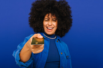 Cheerful young woman holding out her credit card in a studio - obrazy, fototapety, plakaty