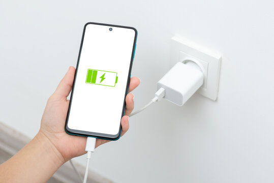 Female holding phone while charging from wall outlet. Charging phone with regular charger concept