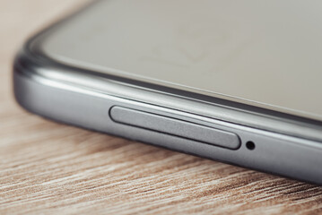 Toned photo of side of a phone with sim card slot tray. Close up of a modern mobile phone, toned image