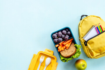 School lunch box with food and backpack, top view