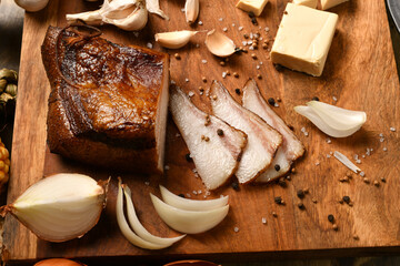 still life of food in a rural style on a dark wood background, sliced lard and garlic, cheese and onion, concept of fresh vegetables and healthy food