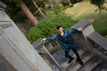 portrait of handsome brunette male model wearing fantasy medieval prince costume, romantic silk shirt. Wandering around historical castle location background with stone staircase.