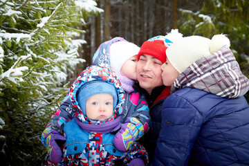 Happy family walking and having fun and photo shoot in park or forest full of snow in a cold winter day