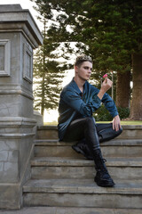 portrait of handsome brunette male model wearing fantasy medieval prince costume, romantic silk shirt. Wandering around historical castle location background with stone staircase.