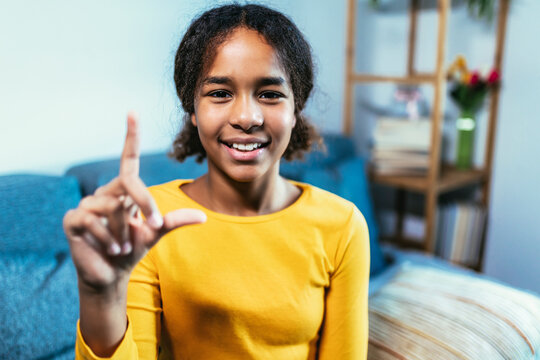 Beautiful smiling black deaf girl using sign language at home