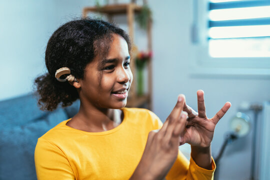 Beautiful smiling black deaf girl using sign language at home