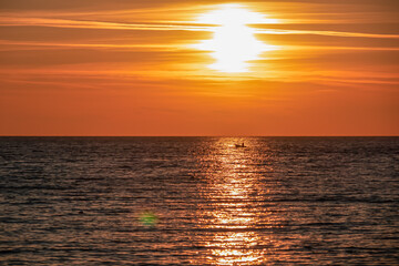 Small fishermen boat with scenic sunset view from Sveti Stefan at Adriatic Mediterranean Sea, Budva Riviera, Montenegro, Europe. Reflection of sun beams on water surface. Summer vacation atmosphere