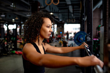 Fototapeta na wymiar Sexy gorgeous african american woman working out with a barbell in the gym, copyspace, sports lifestyle, wrestling, be in good shape