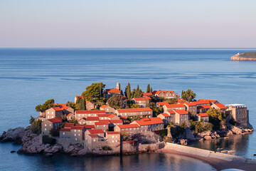Panoramic view of idyllic island Sveti Stefan after sunrise in Bay of Budva, Adriatic Mediterranean...