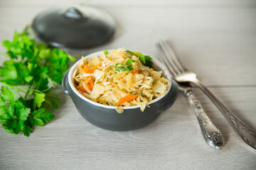 Braised cabbage with carrots, onions and herbs in a ceramic bowl