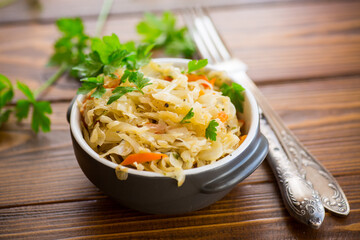 Braised cabbage with carrots, onions and herbs in a ceramic bowl