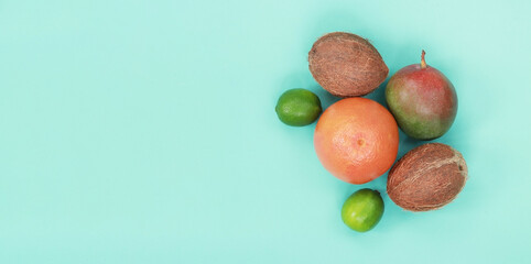 Tropical fruits, top view on a blue background. Grapefruit, coconuts, limes and mangoes on a horizontal light background