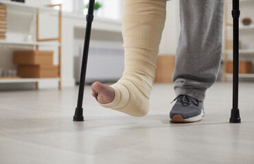 Person with a broken leg walks with crutches. Unrecognizable young man with an injured leg in a...