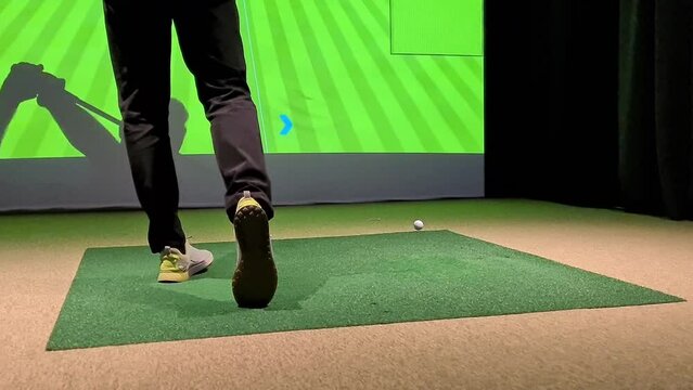 Professional male golfer playing golf indoors in golf simulator closeup. training field with screen