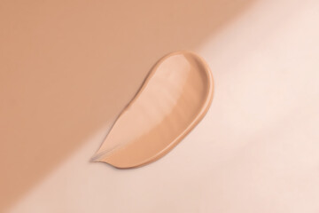 Delicate Light beige smear of tonal foundation on beige background. Sand smudge of tone. Beautiful pastel BB cream stroke. Cosmetic products for makeup and skin care. Cosmetology. Closeup.