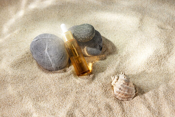 bottle with an essential oil pipette and stones on the sand with light effects