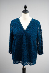 Dark blue top with lace hanging on a headless mannequin. isolated by a light gray or white...