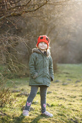 Caucasian little girl in walks in the park in the rays of the setting sun. A child in a red hat...