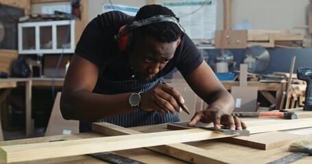 Young focused African carpenter measure his new deign project