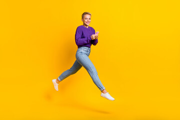 Plakat Full body portrait of excited energetic lady jump rush hold use telephone isolated on yellow color background