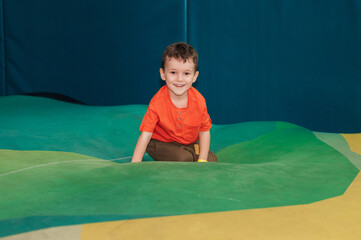 A happy boy jumps on a trampoline in an entertainment center.