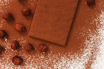 Hazelnuts with a chocolate bar sprinkled with cocoa on a white background