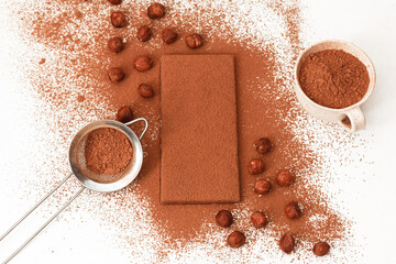 Hazelnuts with a chocolate bar, strainer, sprinkled with cocoa on a white background