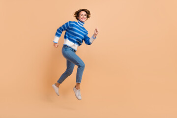 Fototapeta na wymiar Full length portrait of active energetic person jumping rush empty space isolated on beige color background