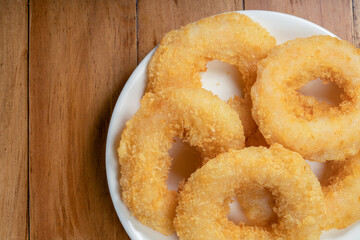 Fried shrimp donut in white plate on wooden table.